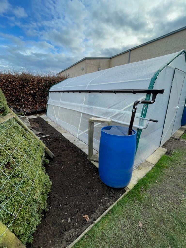 Rain gutter for rainwater collection fixed to a polytunnel.